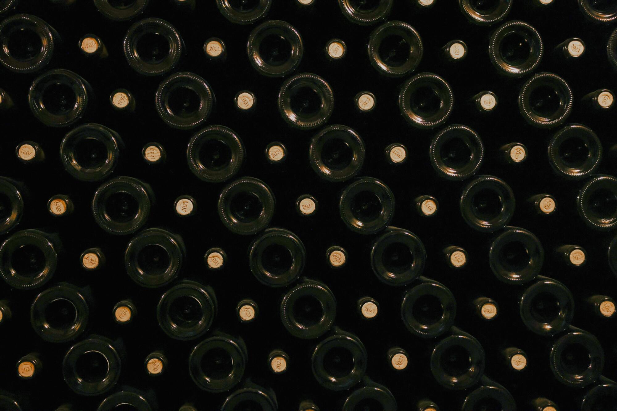 A closeup of wine bottles stacked together.
