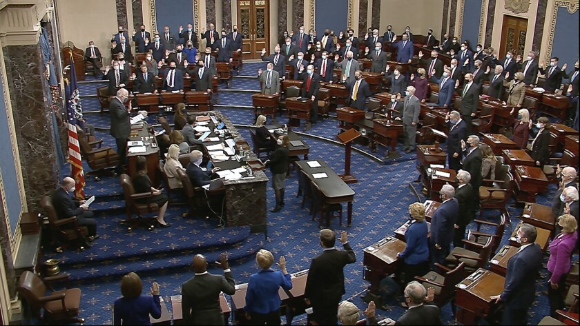 An overview of the Senate chamber with members in masks holding up their right hands.