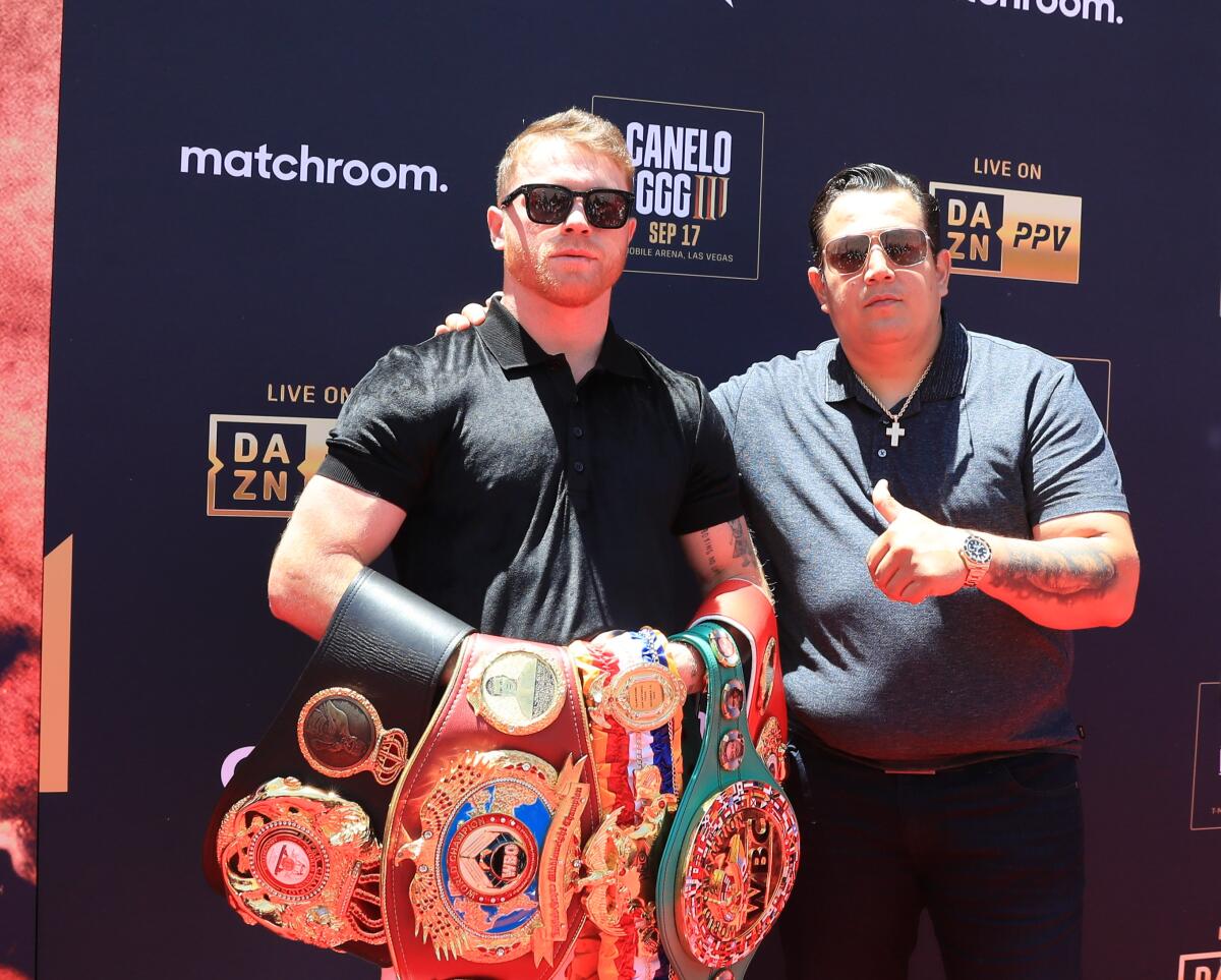 Canelo Alvarez and his trainer Eddy Reynoso show off his championship belts.