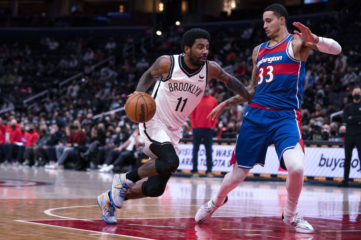 Brooklyn Nets guard Kyrie Irving (11) drives to the basket against Washington Wizards forward Kyle Kuzma (33) during the first half of an NBA basketball game Wednesday, Jan. 19, 2022, in Washington. (AP Photo/Evan Vucci)