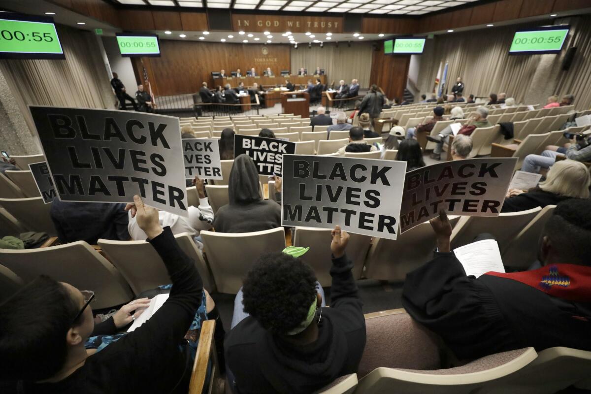 Protesters with signs at a Torrance City Council meeting  after a police shooting