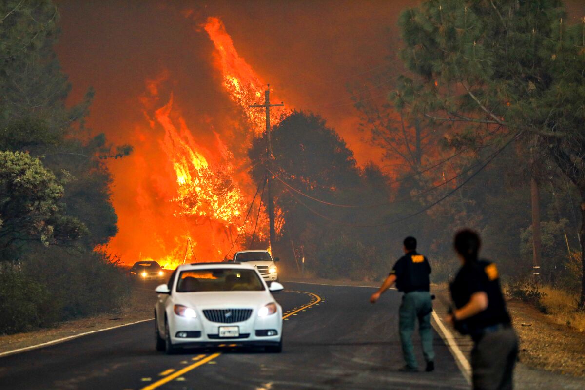 Sheriff deputies yell to drivers to evacuate the area off of Pentz Road during the Camp Fire in Paradise, California
