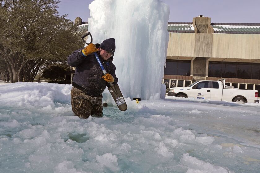 City of Richardson worker Kaleb Love breaks ice on a frozen fountain Tuesday, Feb. 16, 2021, in Richardson, Texas. Temperatures dropped into the single digits as snow shut down air travel and grocery stores. (AP Photo/LM Otero)