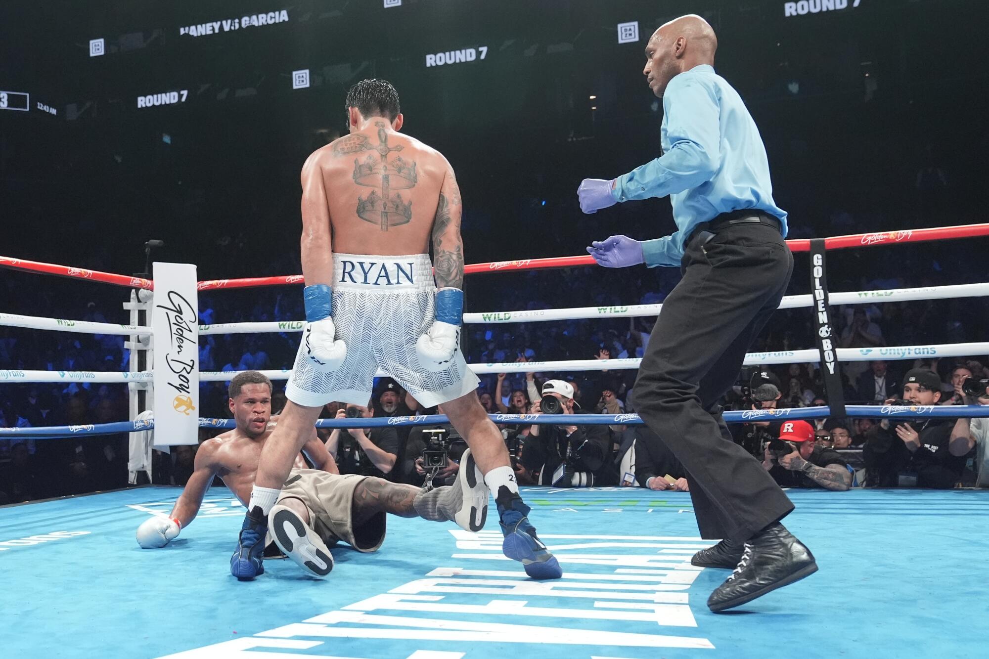 Ryan Garcia stands over Devin Haney after knocking him down during the seventh round