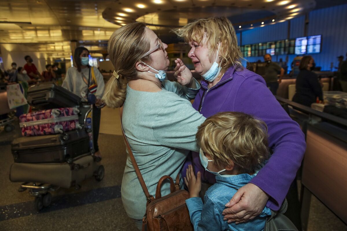 Two women and a boy embracing at Los Angeles International Airport