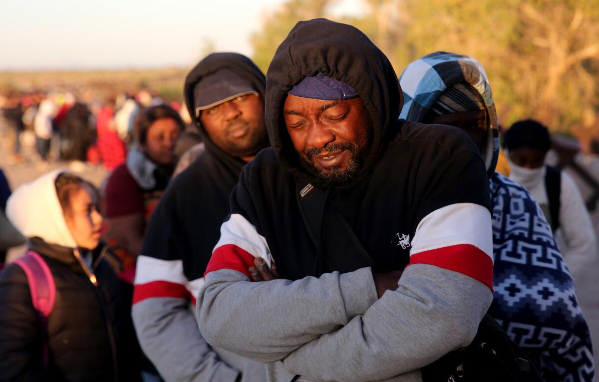 A man standing with arms crossed in a long line of people