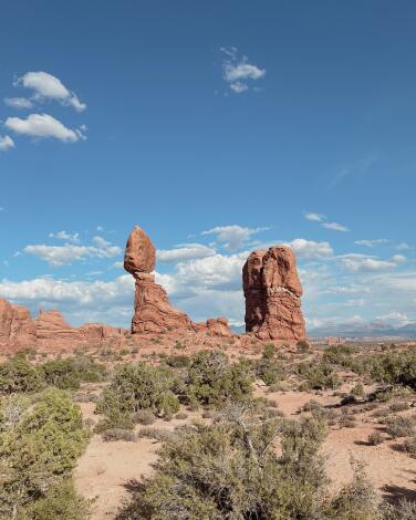Balanced Rock, an iconic formation topped by a 3,600-ton boulder, under a blue sky with scattered clouds