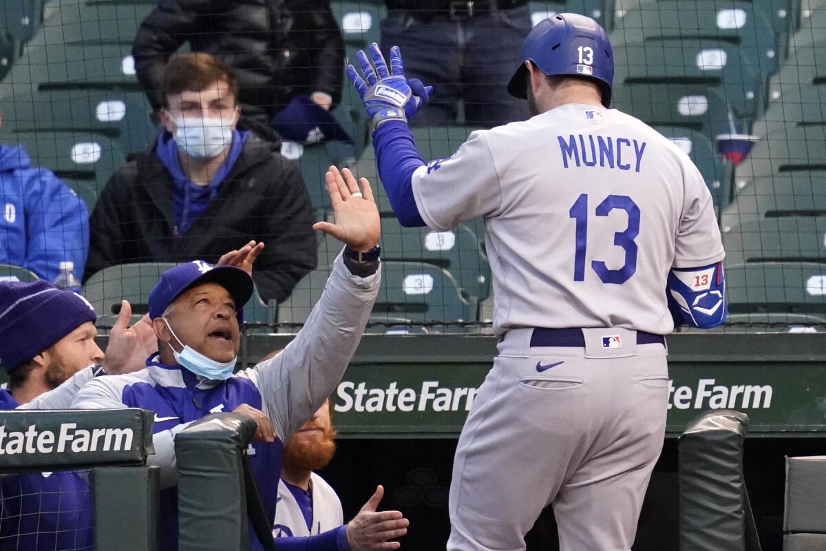 Los Angeles Dodgers manager Dave Roberts, left, congratulates Max Muncy after his solo home run during the fourth inning of a baseball game against the Chicago Cubs in Chicago, Wednesday, May 5, 2021. (AP Photo/Nam Y. Huh)