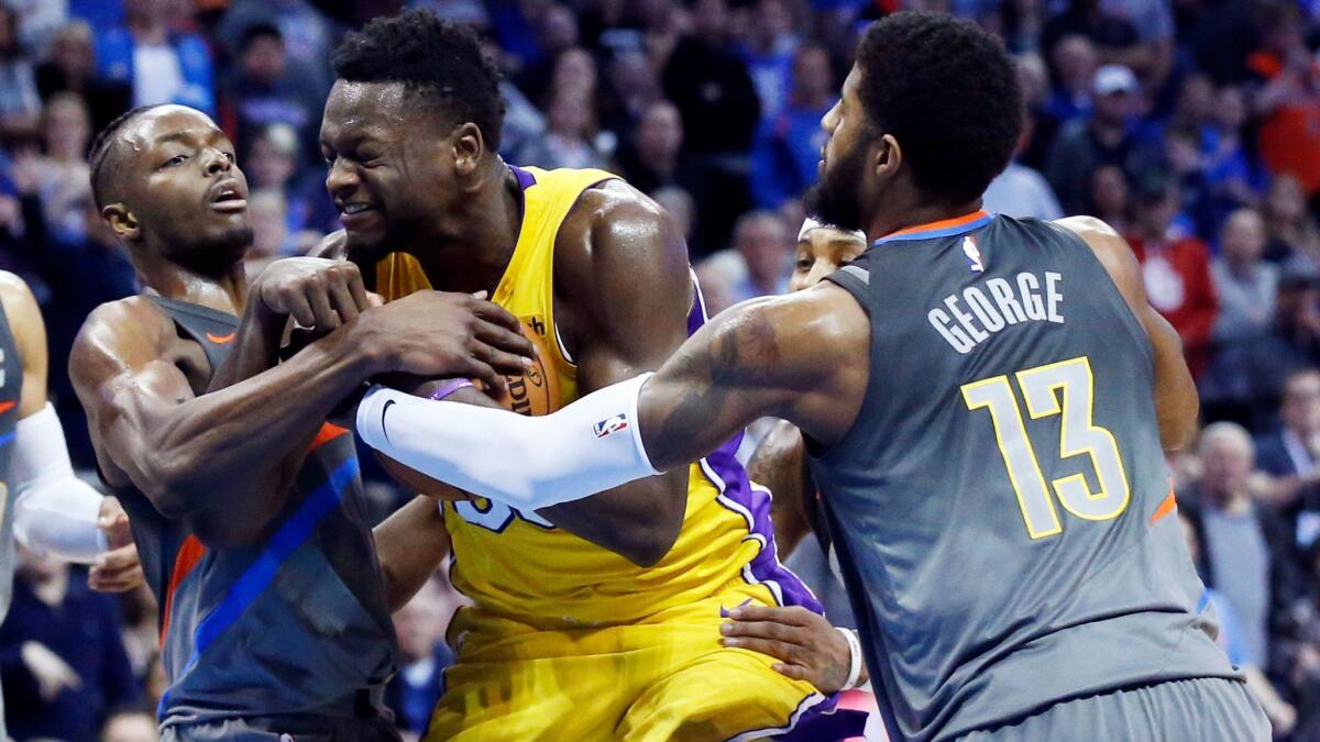 Lakers forward Julius Randle keeps the ball away from Oklahoma City's Jerami Grant, left, and Paul George on Feb. 4.