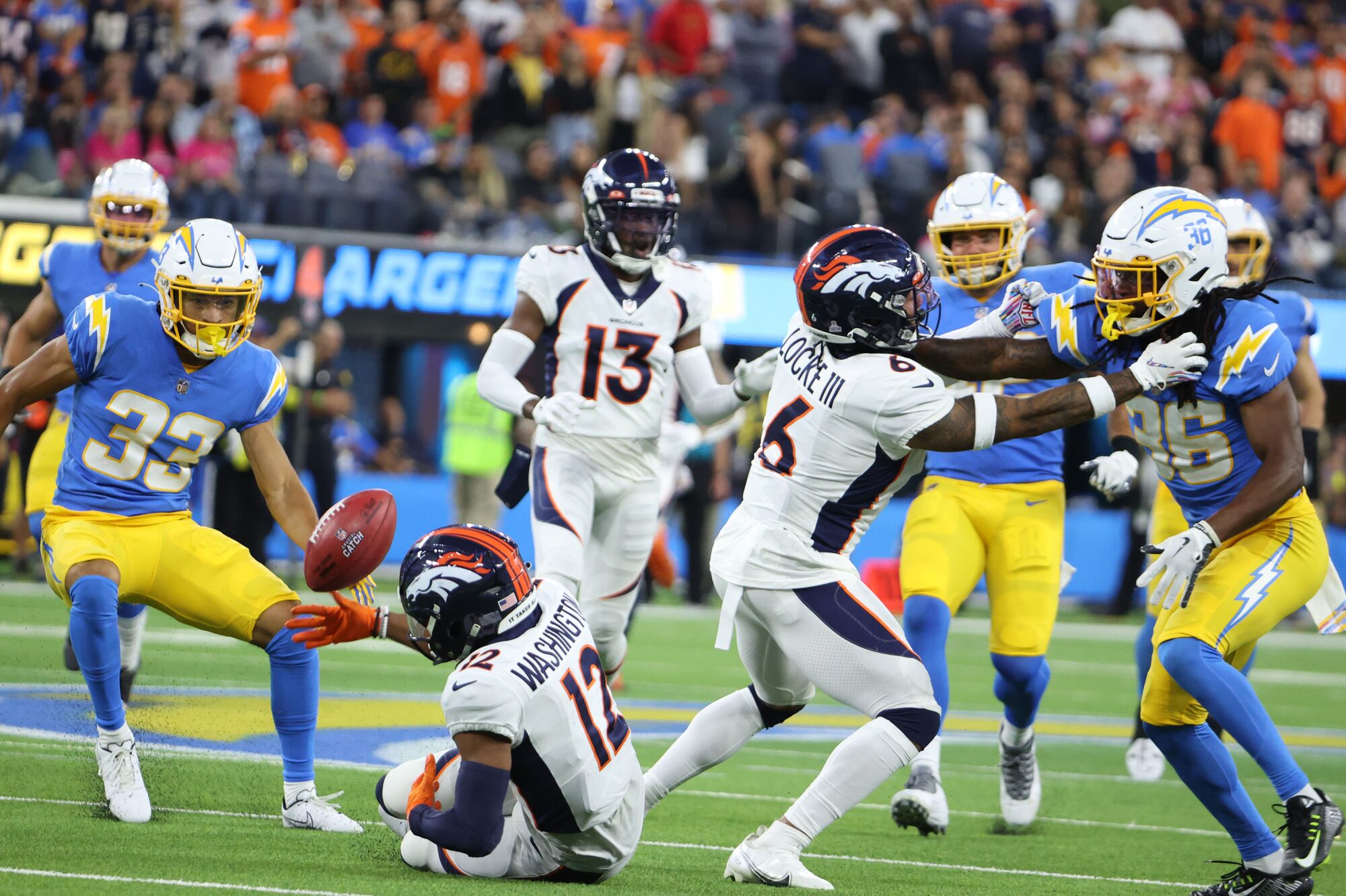 Broncos wide receiver Montrell Washington fumbles a punt as Chargers cornerback Deane Leonard closes in to recover.