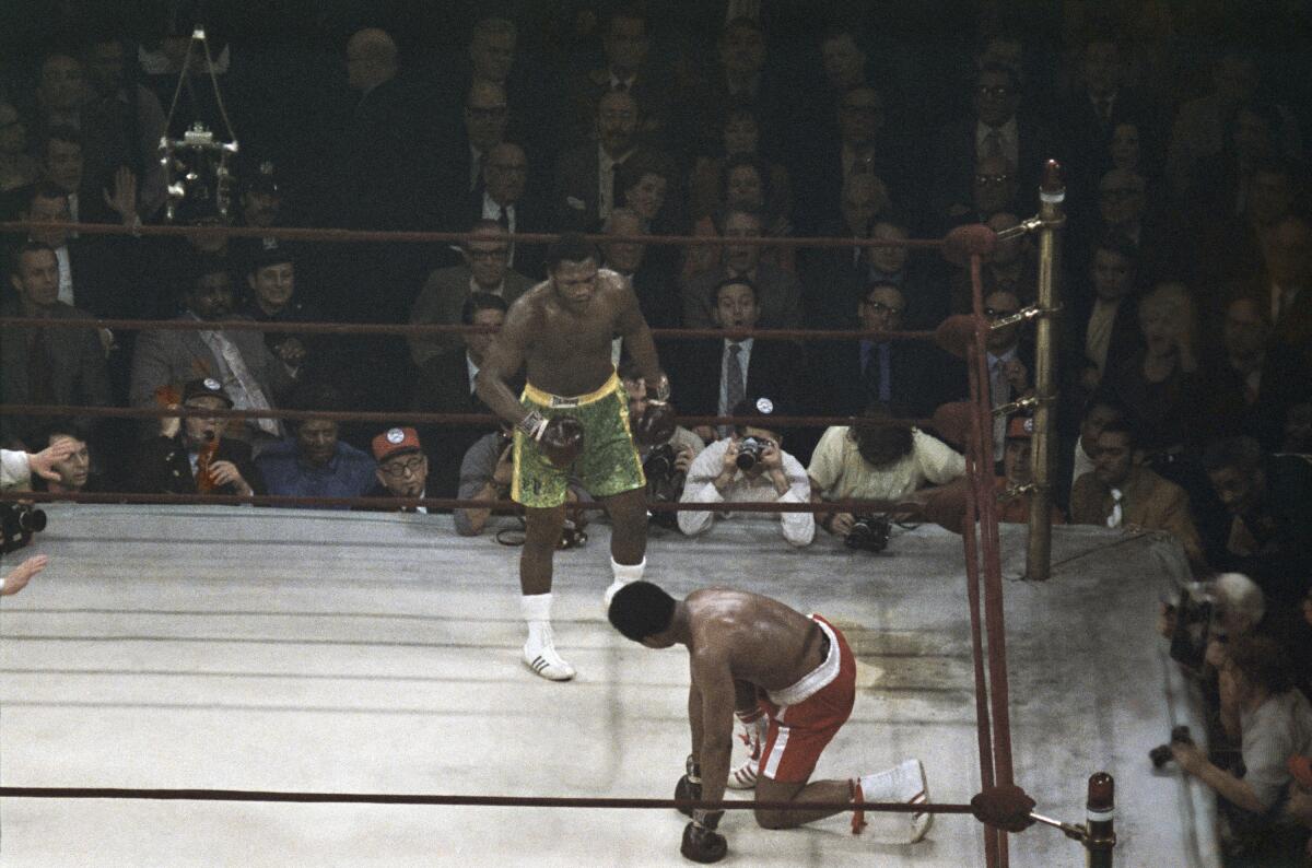 Muhammad Ali looks up toward Joe Frazier after getting knocked down