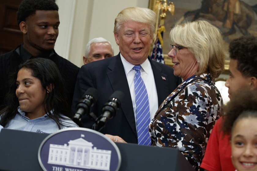 President Donald Trump stands with Education Secretary Betsy DeVos in the Roosevelt Room of the White House in Washington, on May 3.