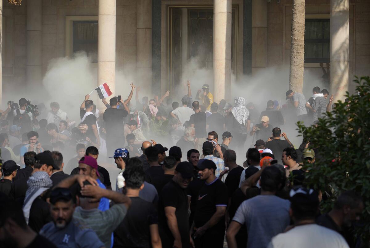 Clouds of tear gas are visible among protesters in Baghdad.