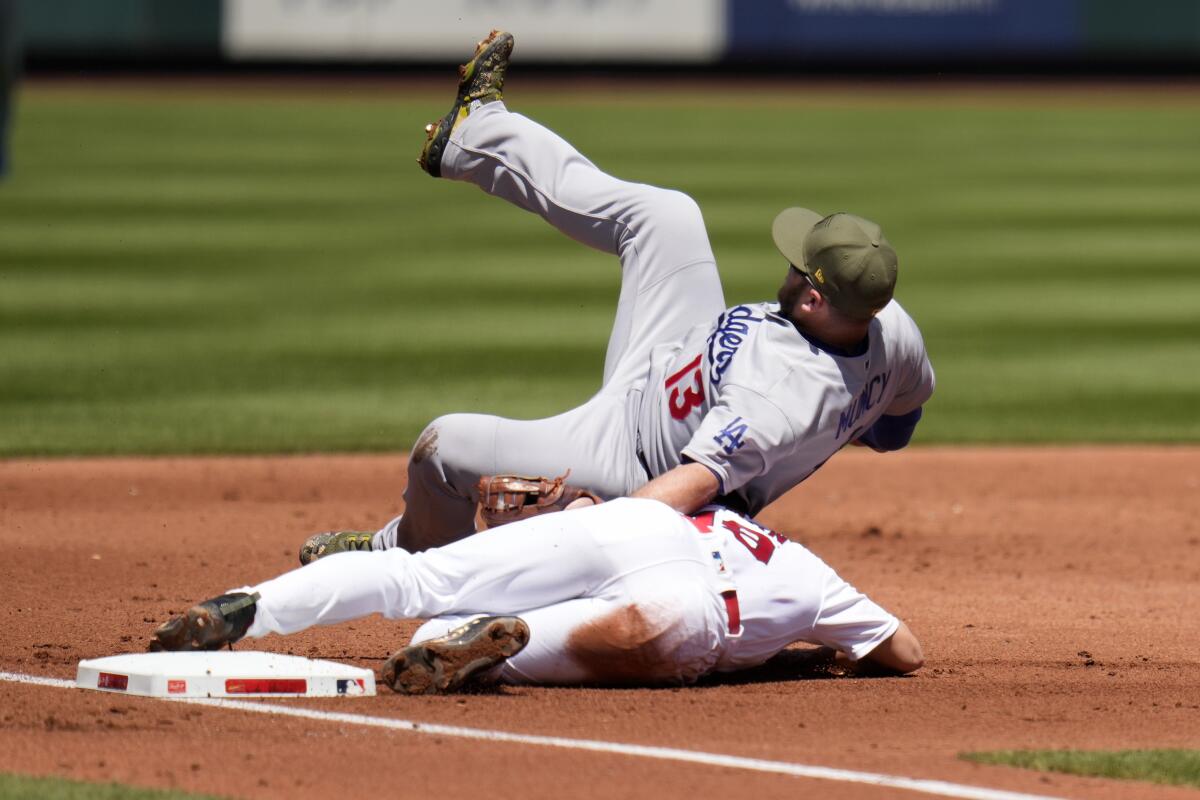 Dodgers third baseman Max Muncy, top, falls after tagging out Cardinals baserunner Tommy Edman.