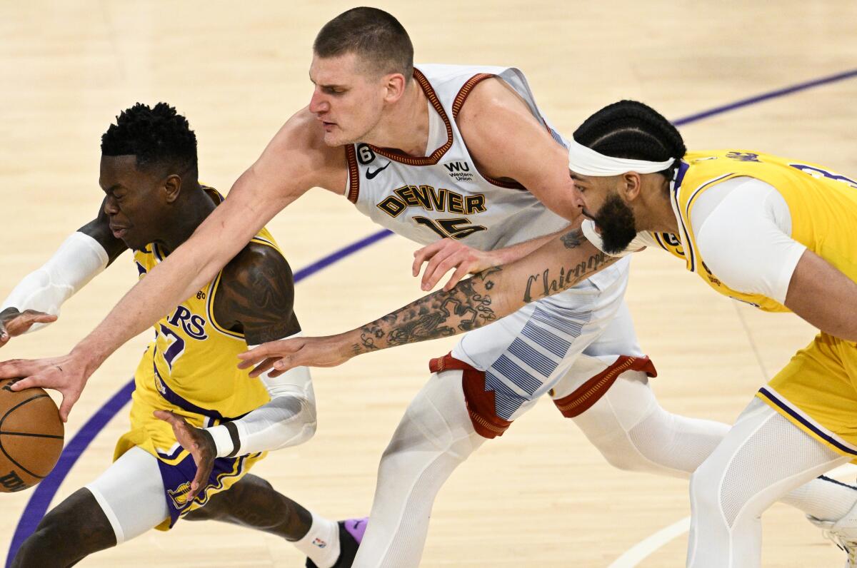 Dennis Schroder, left, battles for the loose ball along with Lakers teammate Anthony Davis and Denver's Nikola Jokic, center.