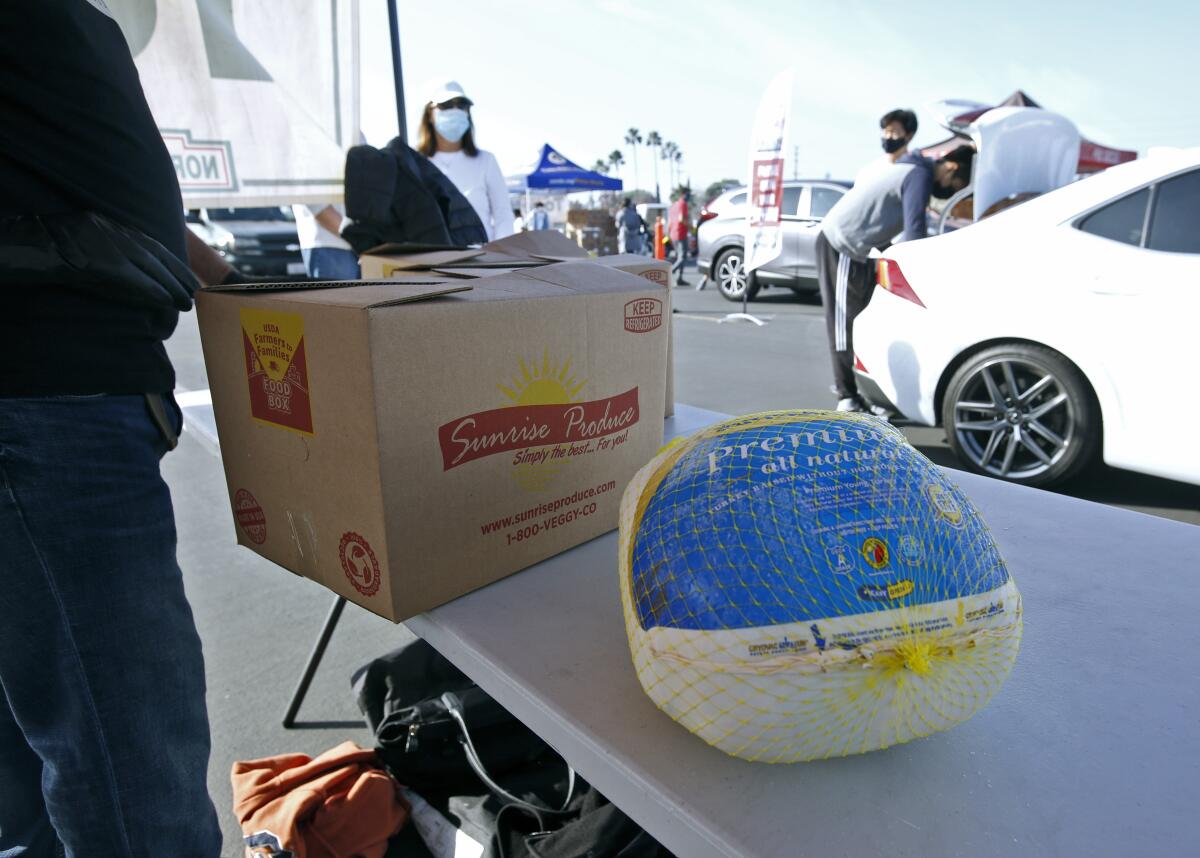 Los voluntarios ayudan a cargar cajas de comida en los vehículos en un evento por el Thanksgiving realizado en en Costa Mesa.