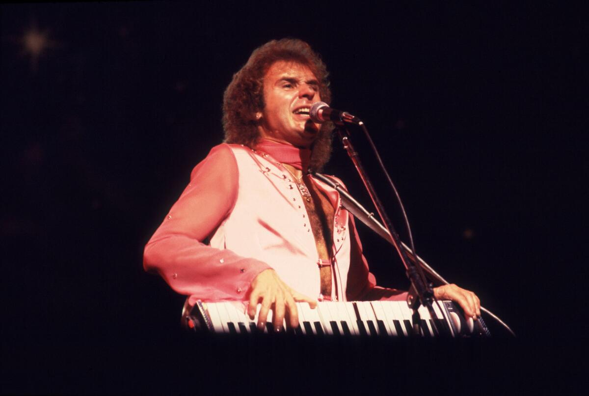 A man playing keyboards and singing onstage