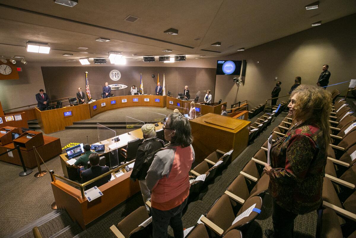 Huntington Beach City Council members and meeting attendees stand for the Pledge of Allegiance.