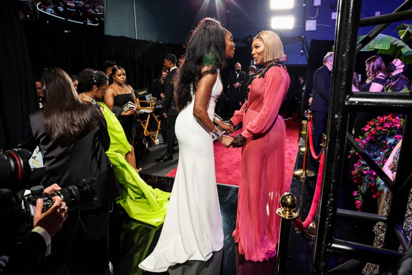 A group of people backstage, including two sisters holding hands.