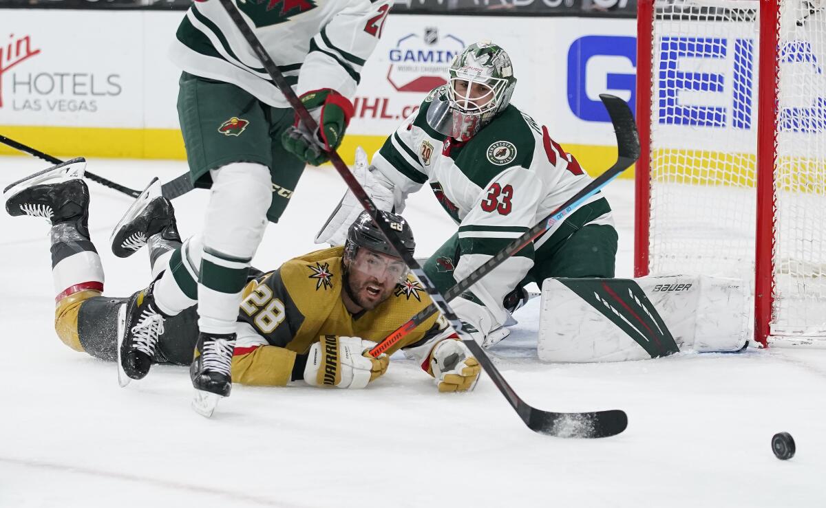 Vegas Golden Knights left wing William Carrier (28) falls into Minnesota Wild goaltender Cam Talbot (33) during the second period of an NHL hockey game Saturday, April 3, 2021, in Las Vegas. (AP Photo/John Locher)