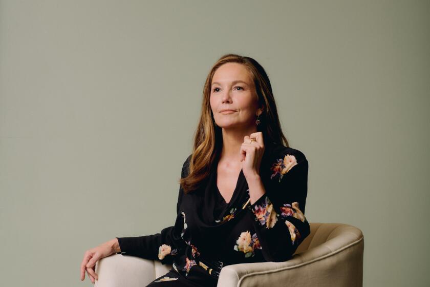 Diane Lane sits in a chair, posing, staring into the distance off camera