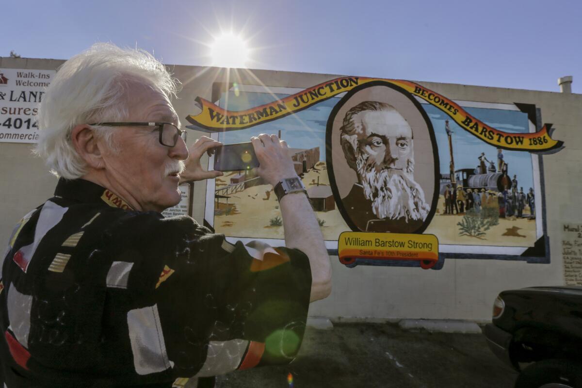 Canadian tourist Wayne Webb stops to take a photo of the mural "Waterman Junction Becomes Barstow, 1886," on a building along Main Street in Barstow.