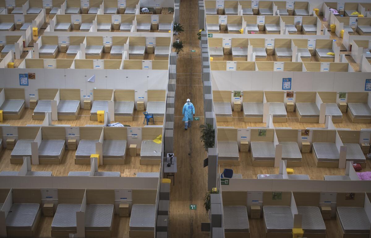 In this March 8, 2020, photo released by Xinhua News Agency, a staff member walks down a corridor of an empty makeshift hospital in Wuhan, central China's Hubei Province. The makeshift hospital converted from a sports venue was recently closed after its last batch of cured COVID-19 patients were discharged. (Xiao Yijiu/Xinhua via AP)