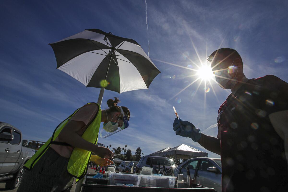 Dr. Richard Dang, right, of the USC School of Pharmacy prepares a vaccine at Dodger Stadium 