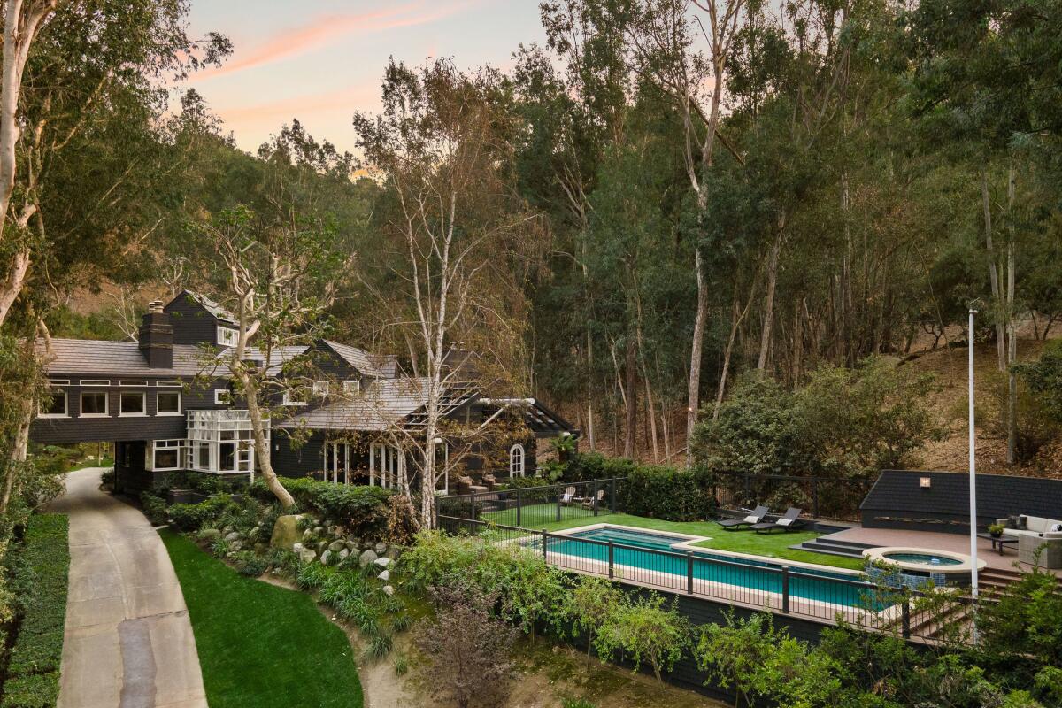 A multistory house with a backyard pool in a wooded area