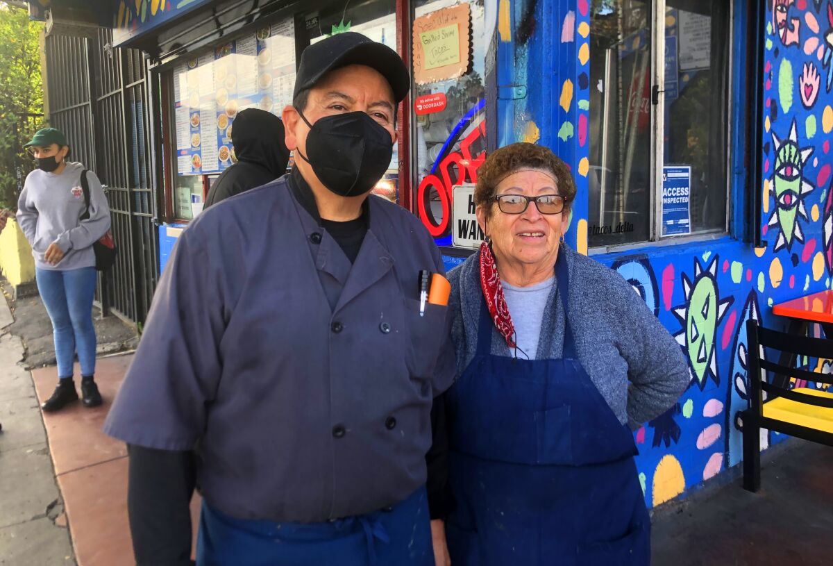 A couple stands for a photo in front of a restaurant.