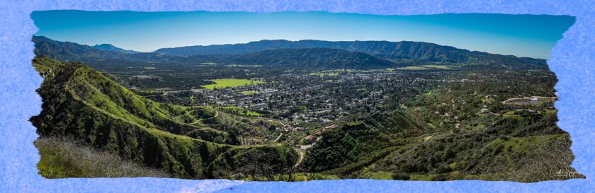 A sweeping of a green valley with blue sky in the background.