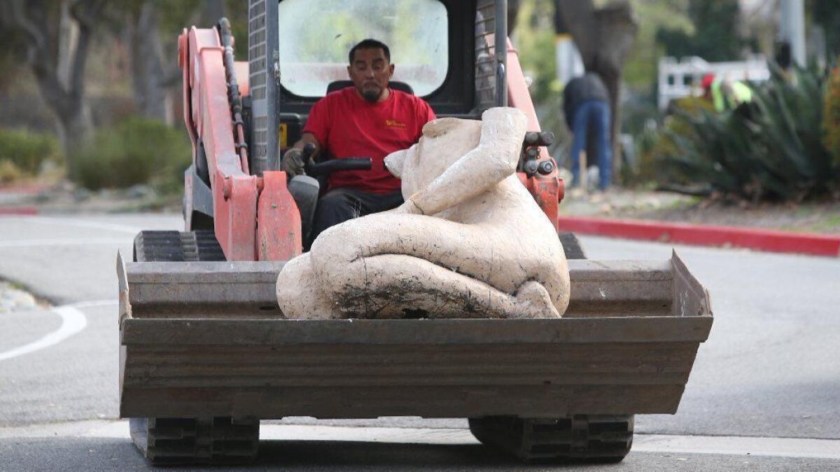 A small bulldozer carries away the lower part of one of the "kneeling women" statues from the front of the Laguna College of Art + Design campus on Wednesday.
