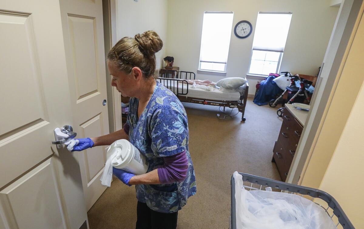 Mina Montano uses disinfectant wipes to clean a room at St. Paul's Plaza in Chula Vista.