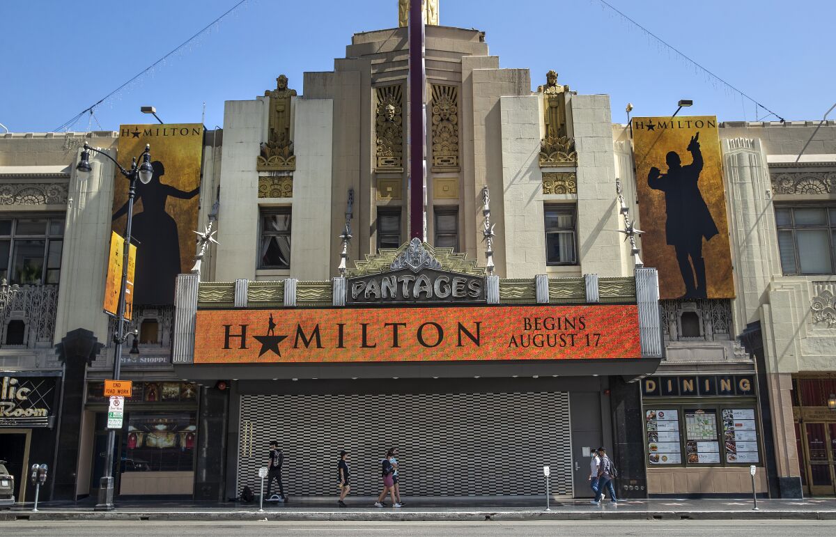 Pedestrians walk past the closed Hollywood Pantages Theatre, whose marquee promotes "Hamilton."
