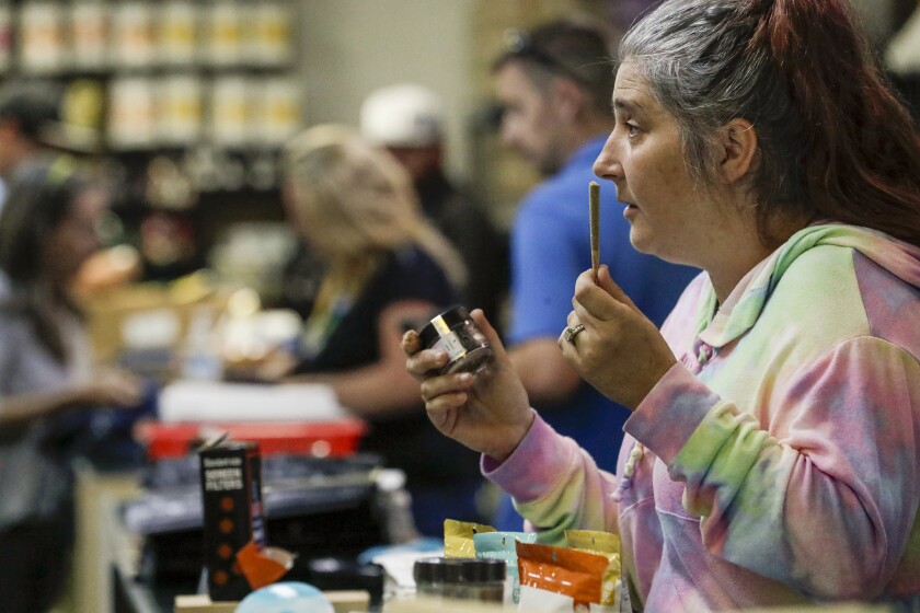 A budtender holds a joint at a cannabis dispensary 