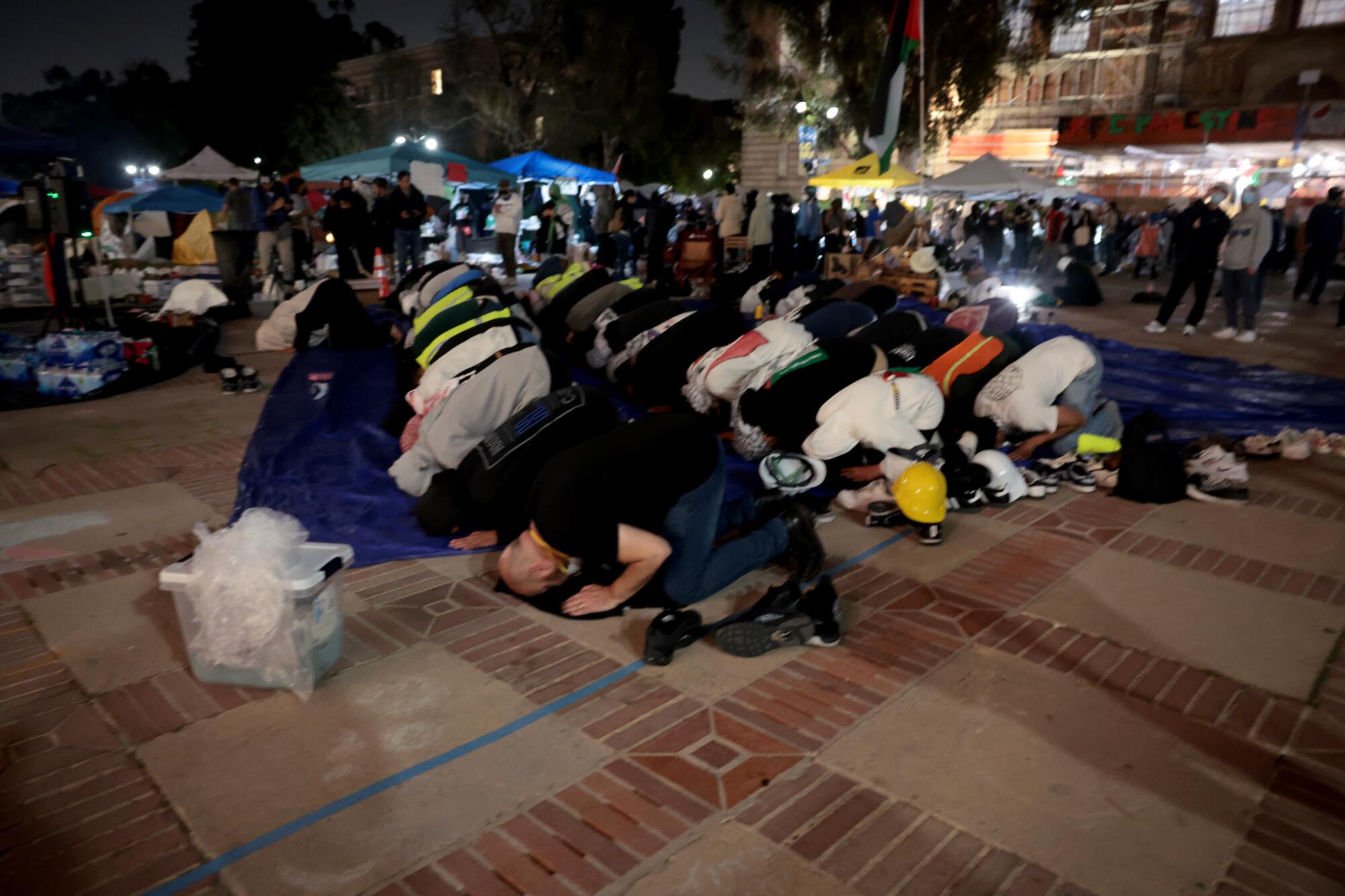 La gente se arrodilla, apoya la cabeza en el suelo y reza en la plaza.