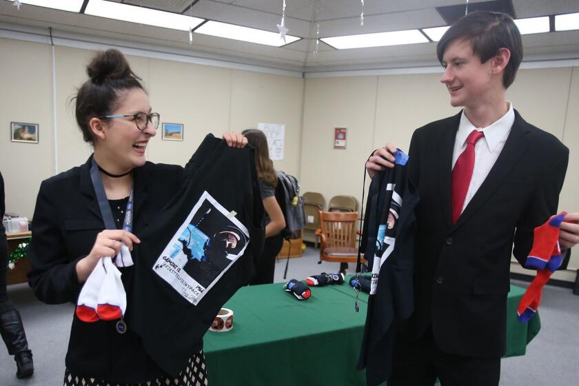 Students Jessi Diment and Colby Peterson, from left, happily open NASA gift bags brought by space industry grad student Alex Coultrup, during the International Space Station program meeting at Brethren Christian High school in Huntington Beach.