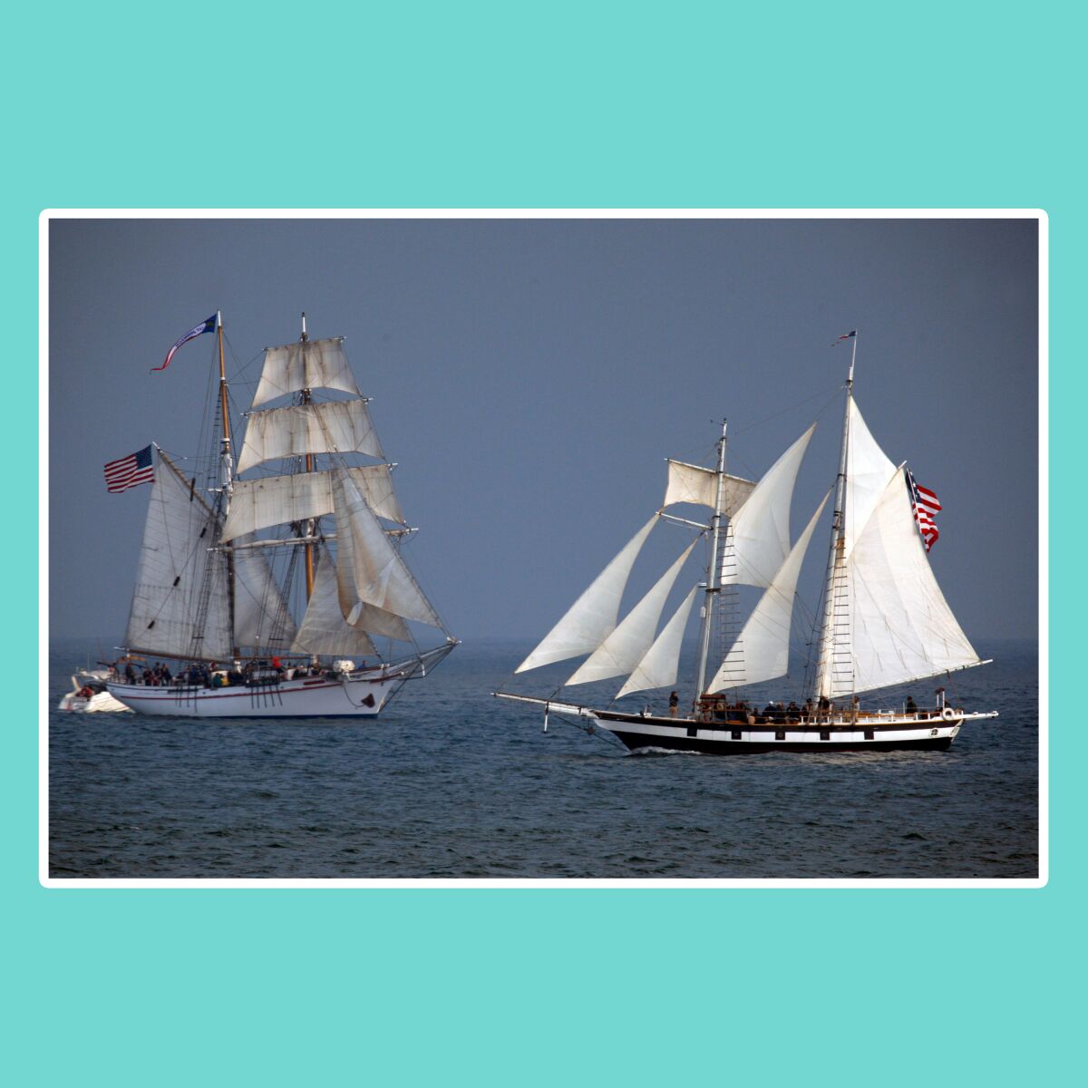 Two full-masted tall ships at sea.