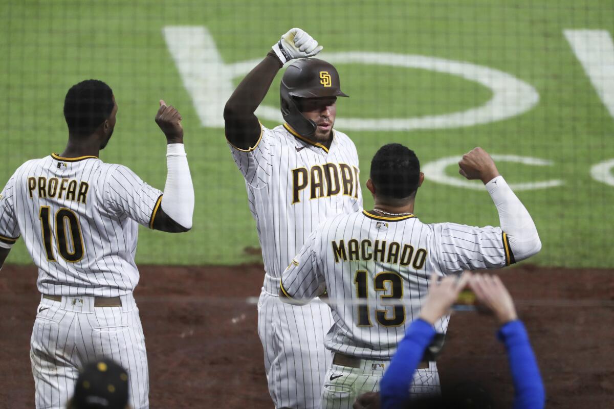San Diego Padres' Victor Caratini, center, is congratulated by Manny Machado, right, after hitting a two-run home run against the San Francisco Giants during the seventh inning of a baseball game Tuesday, April 6, 2021, in San Diego. (AP Photo/Derrick Tuskan)