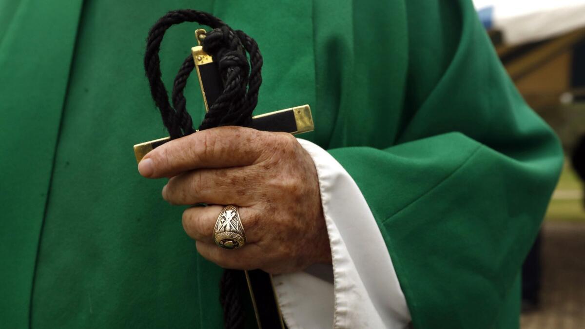 Father Roy Snipes carries a cross after Friday Mass.