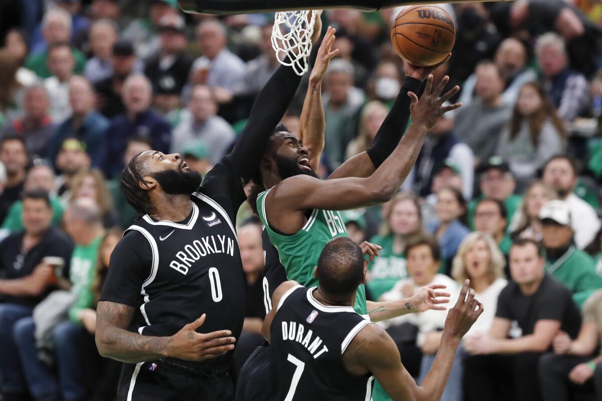 Boston Celtics' Jaylen Brown shoots against Brooklyn Nets' Andre Drummond and Kevin Durant.