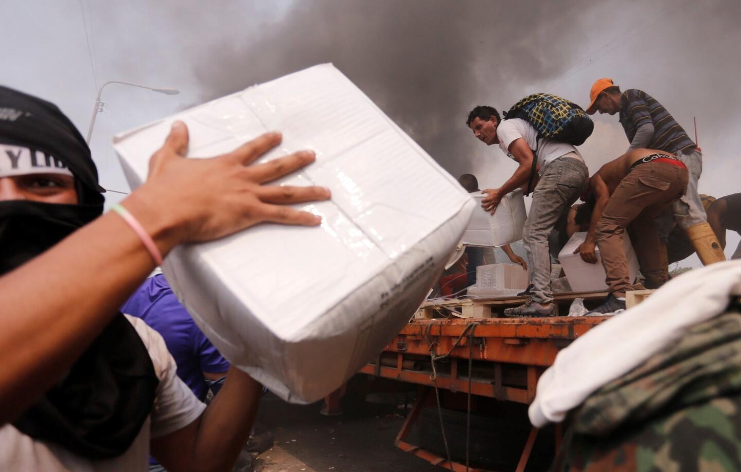 People try to take part of the humanitarian aid from a truck that was set on fire in Urena, Venezuela, on Saturday. Two trucks with aid requested by the opposition were burned by Venezuelan security forces at a border bridge with Colombia.