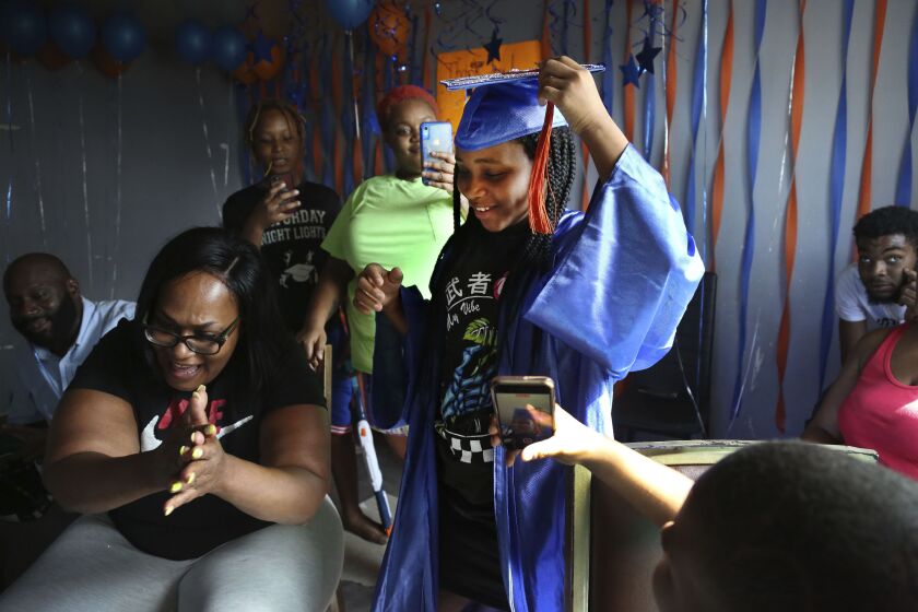 Sharawn Vinson, front left, and family members and friends cheer for her daughter, Maddison Washington, 11, as they watch her virtual graduation from middle school in the living room of their three-bedroom apartment in the Brooklyn borough of New York on Friday, Aug. 21, 2020. After months of pandemic isolation and living with the fear of hunger as bills piled up, Vinson and her kids continued volunteering to help feed their own community. (AP Photo/Jessie Wardarski)