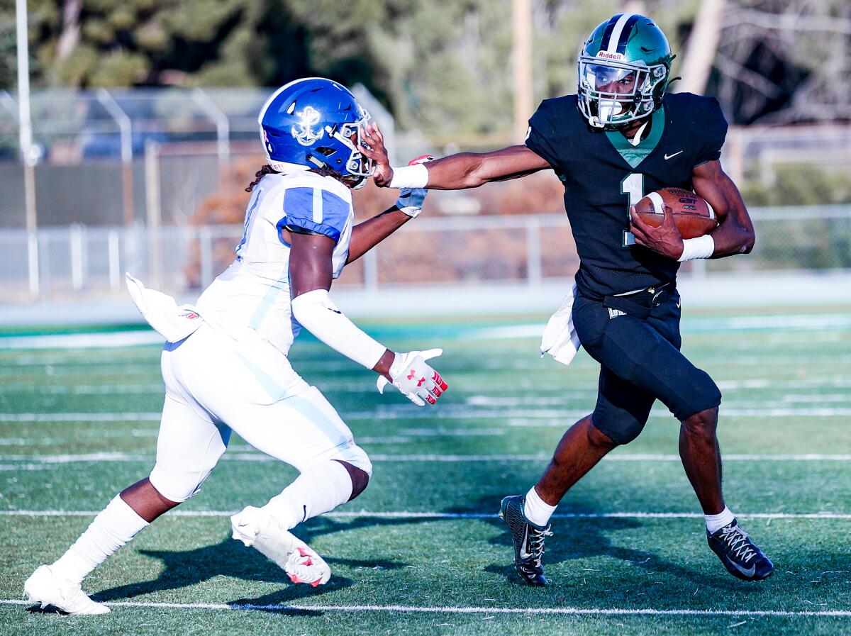 Running back Dijon Stanley of Granada Hills stiff-arms Palisades defender.