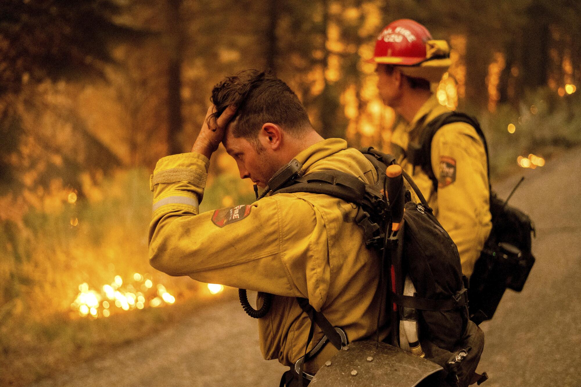 Firefighter Jesse Forbes rubs his head while battling the Dixie fire near Prattville in Plumas County, Calif.