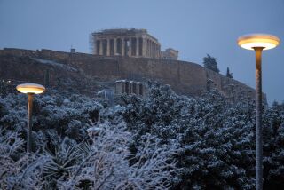 La nieve cubre un árbol en el centro de Atenas, con el antiguo templo del Partenón, en la Acrópolis, al fondo, en Grecia, el lunes 6 de febrero de 2023. (AP Foto/Thanassis Stavrakis)