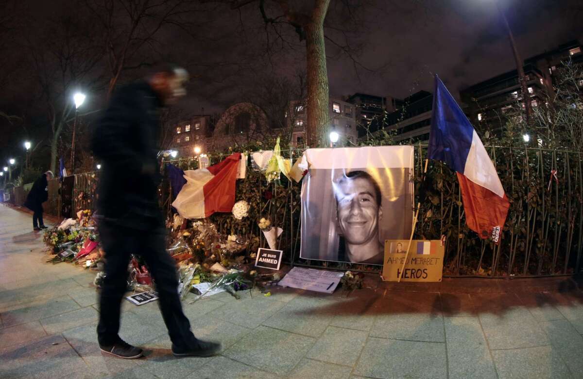 A man walks past a makeshift memorial for French policeman Ahmed Merabet on Jan. 11 near the site where the officer was shot to death by gunmen close to the headquarters of the French satirical weekly Charlie Hebdo four days earlier.