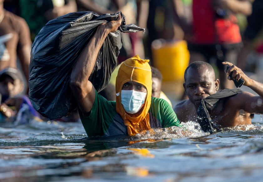 برخی از مردم هائیتی در حالی که وسایل خود را در یک کیسه زباله نگه می دارند سعی می کنند از ریو گرانده عبور کنند.