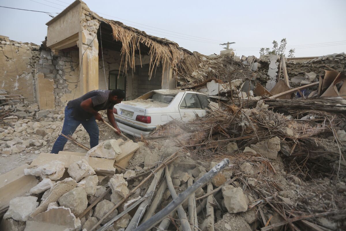 A man digs through rubble outside a badly damaged home 