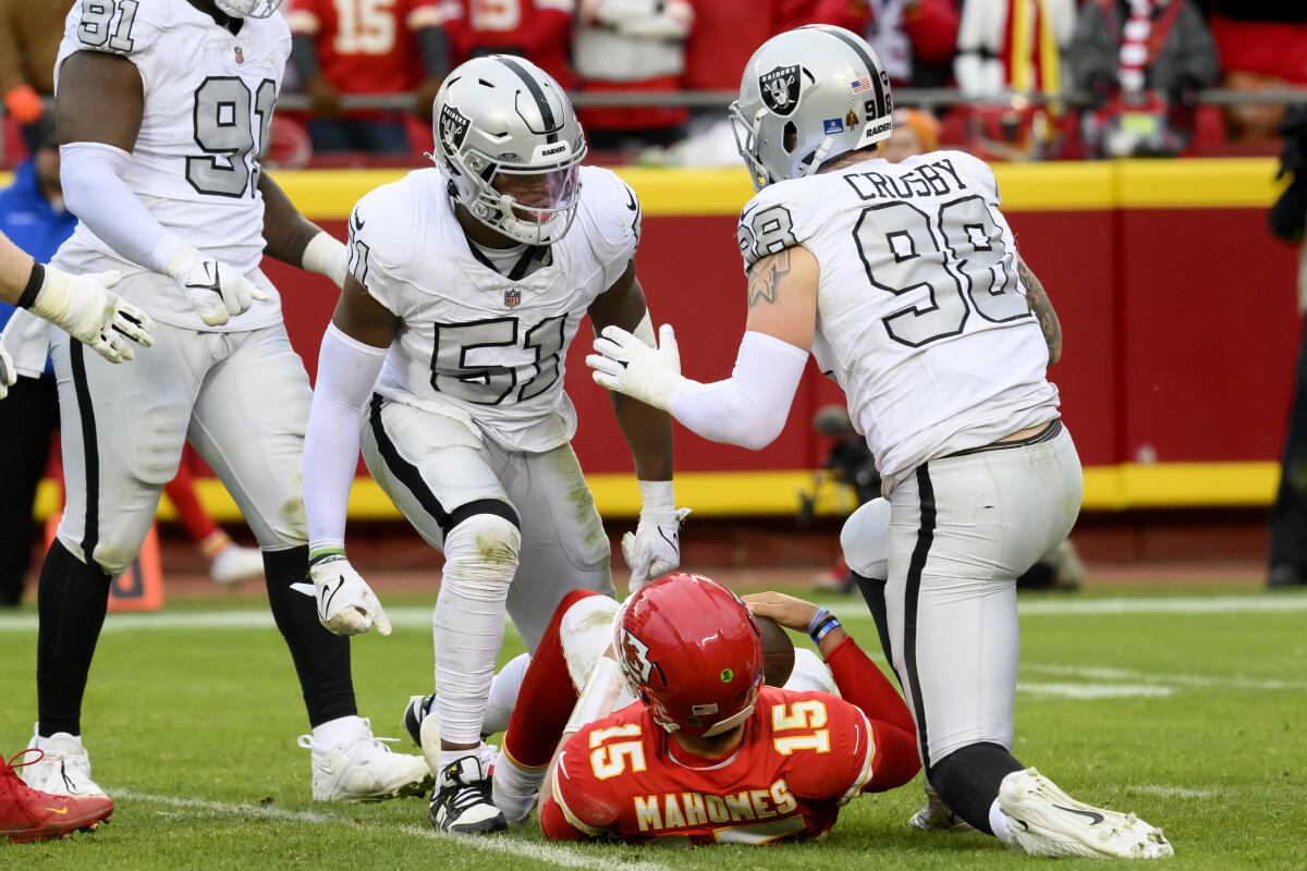Raiders' Malcolm Koonce celebrates with Maxx Crosby over Chiefs quarterback Patrick Mahomes, who is on the ground.